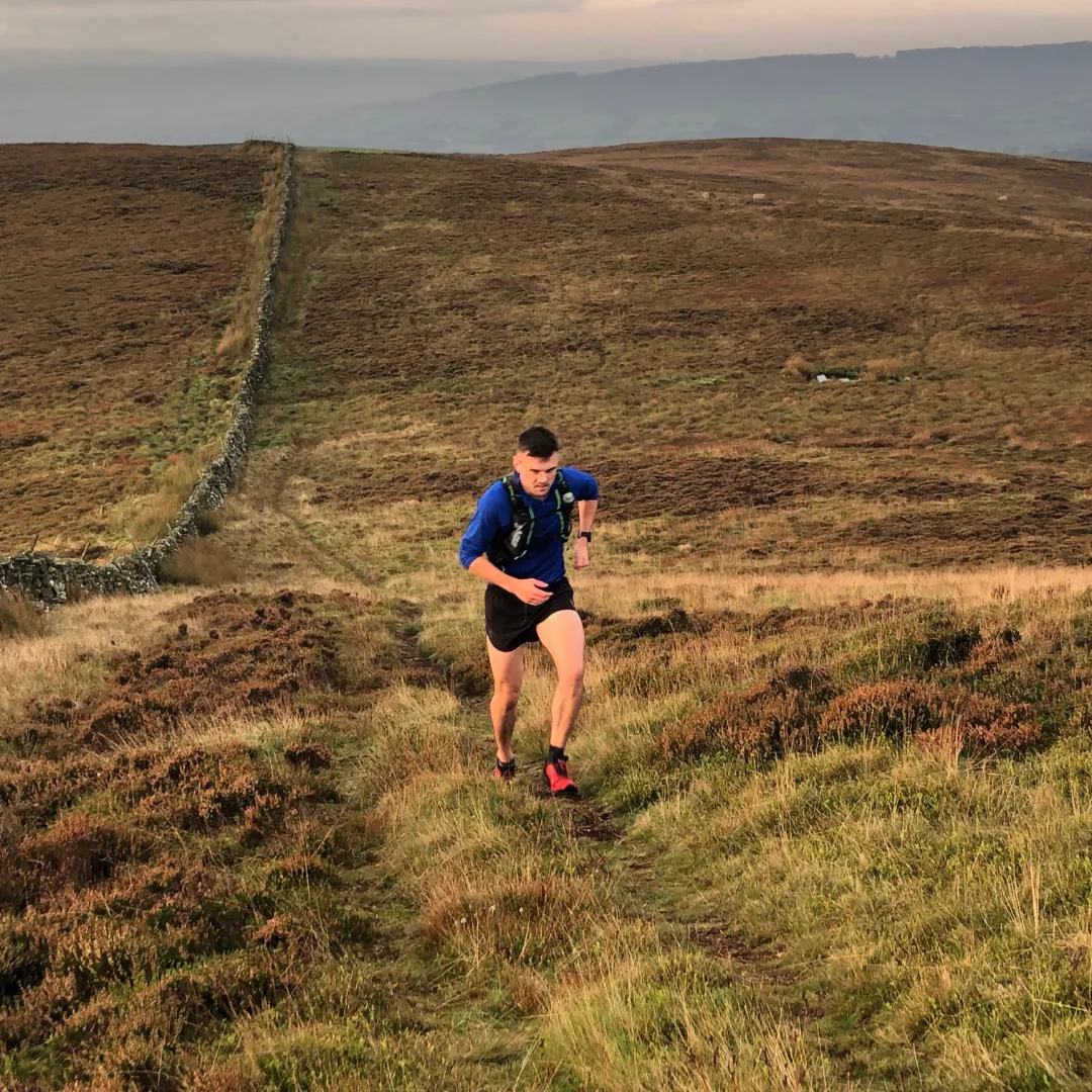 Sam trail running uphill in a rural landscape